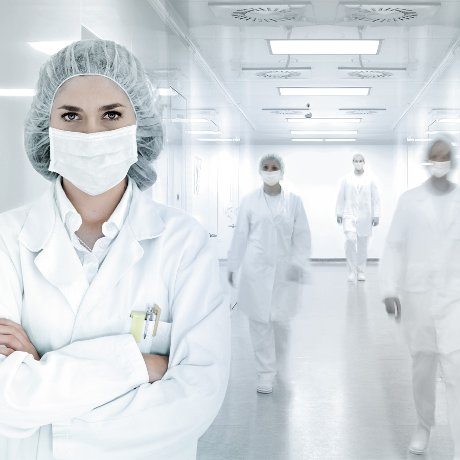 Frau steht mit Schutzkleidung in einem hygienisch sauberen Raum.