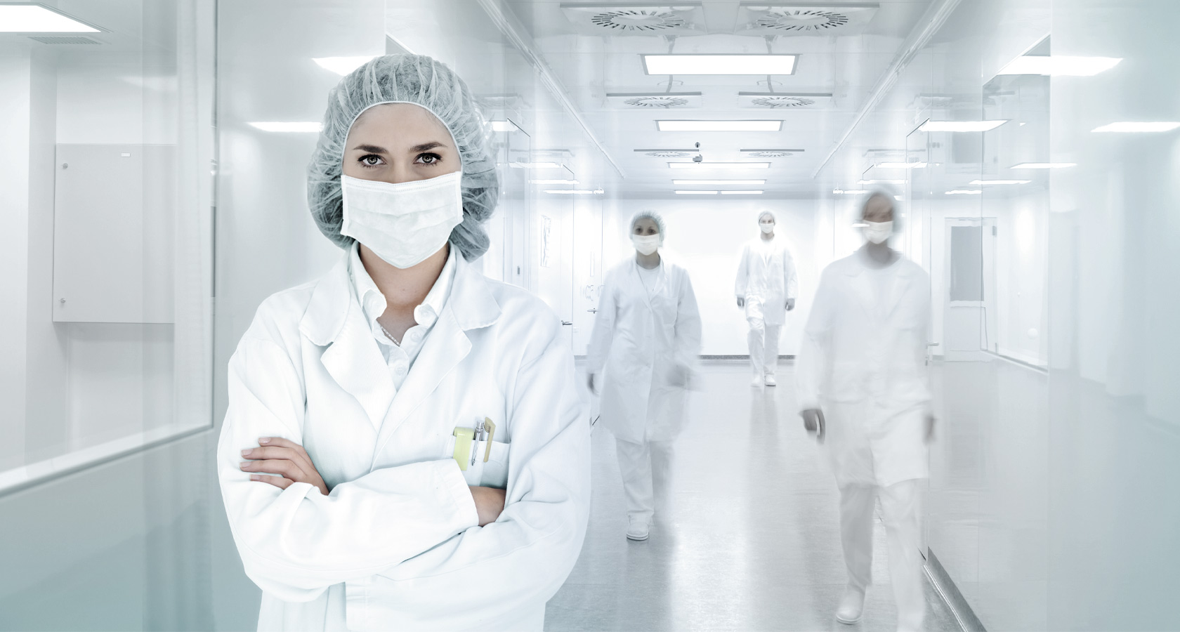 Frau steht mit Schutzkleidung in einem hygienisch sauberen Raum.