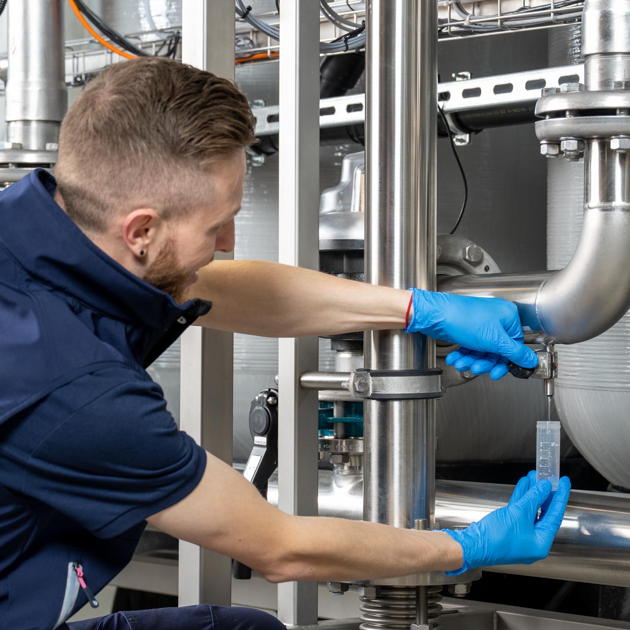 BWT Servicetechniker entnimmt eine Wasserprobe an einer industriellen Wasseranlage zur Legionellenanalyse.
