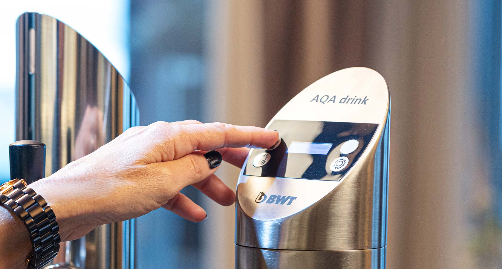 Hand drückt einen Knopf an der BWT WasserBar.