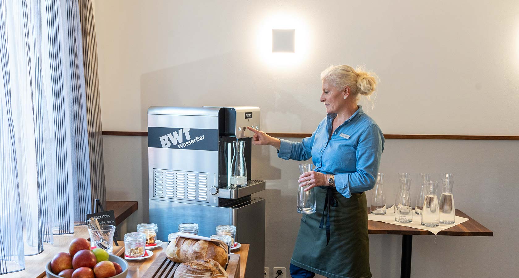 Frau bezieht Wasser an einer BWT WasserBar.