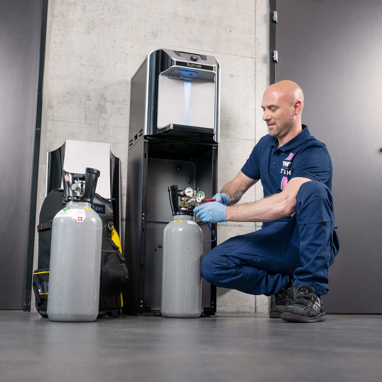 Techniker arbeitet an einem Wasserspender. 