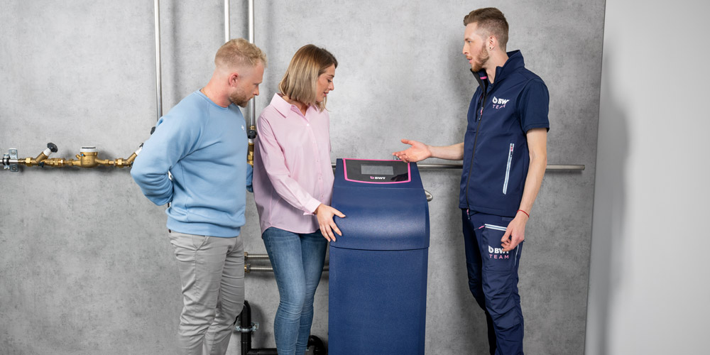 Mann, Frau und BWT Servicetechniker stehen neben einer Entärtungsanlage.