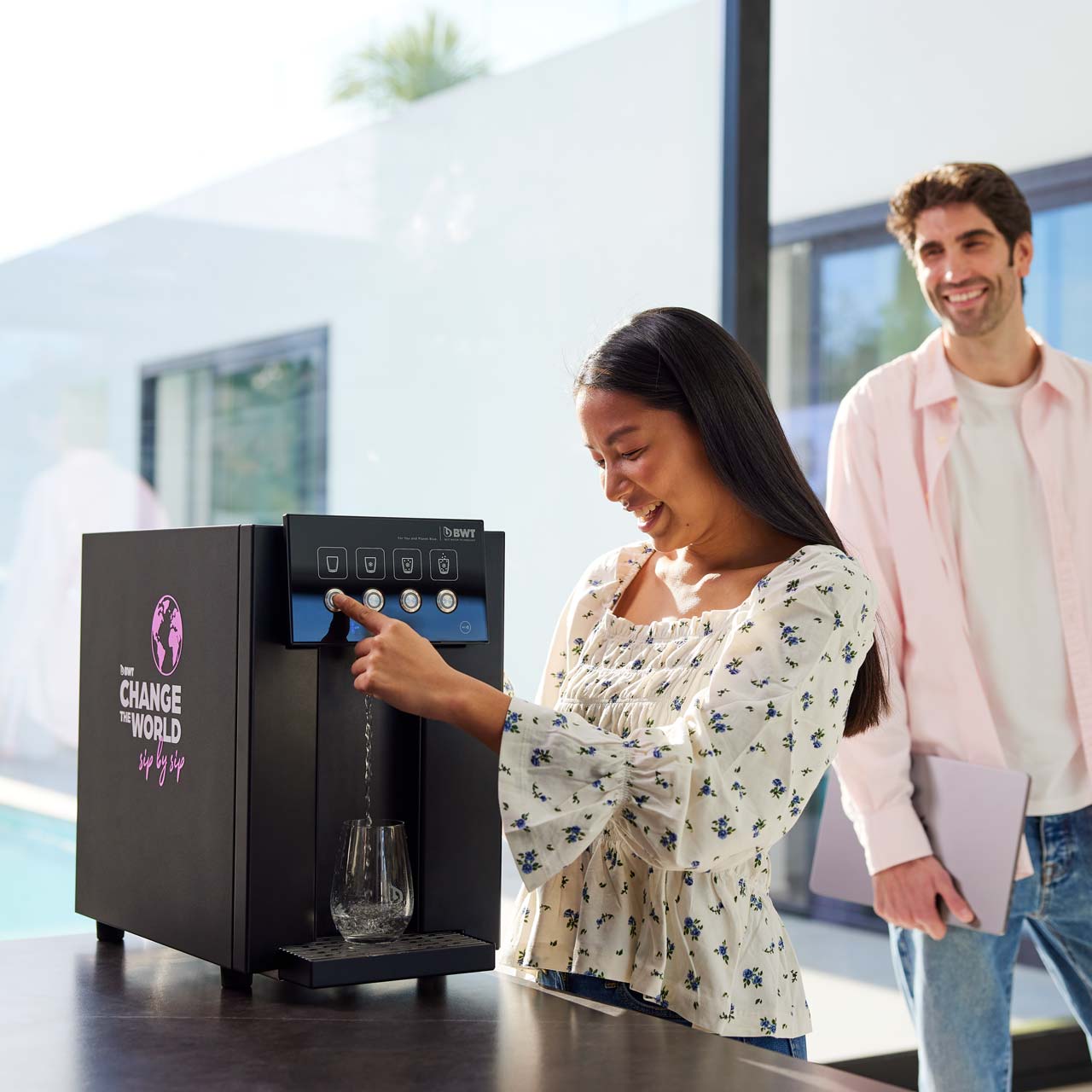 Frau bezieht Wasser an einem Wasserspender.