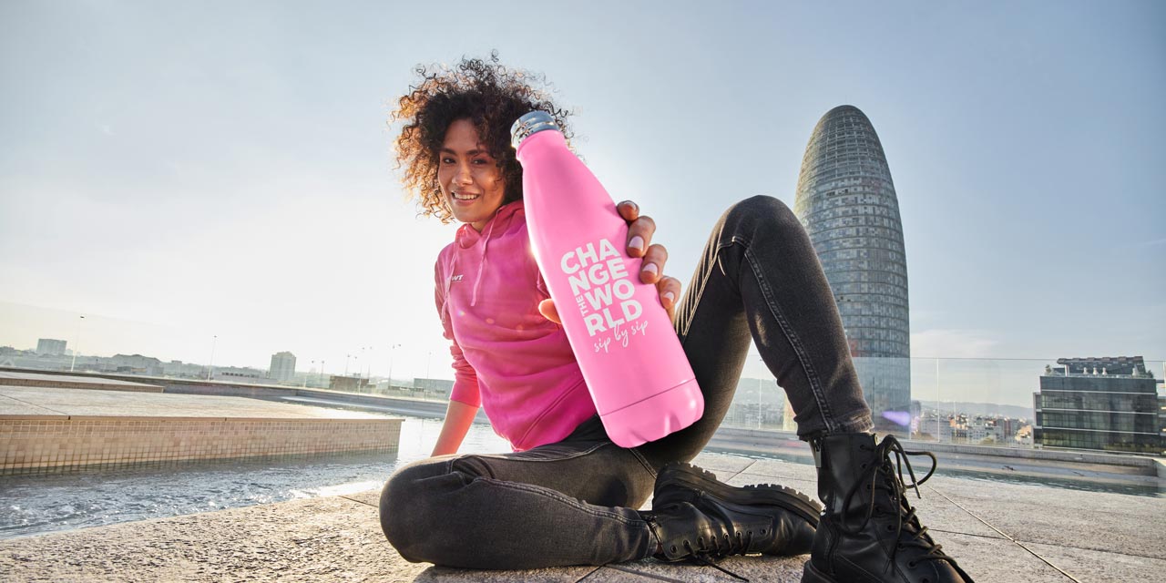 Frau hält pinke BWT Flasche und sitzt am Boden.