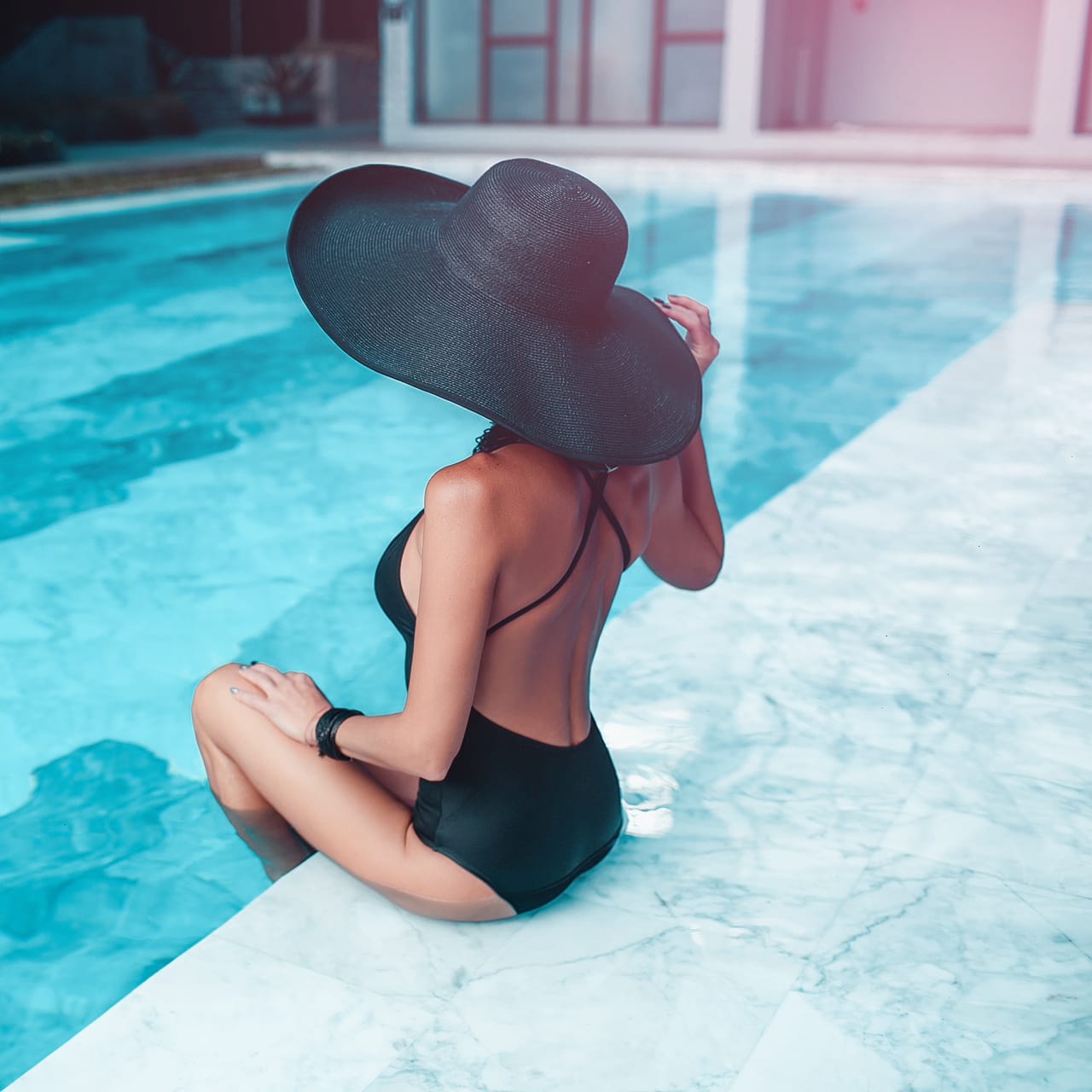 Frau am Pool mit Hut