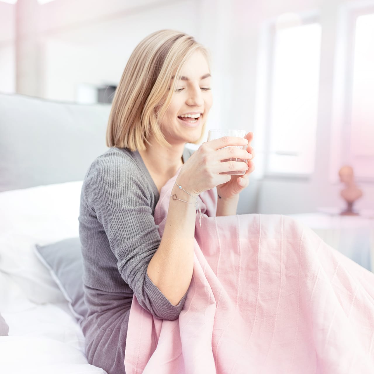 Frau trinkt Wasser im Bett