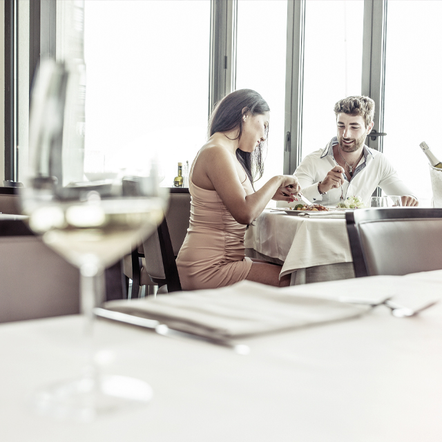 Une femme et un homme sont assis au restaurant et admirent la vaisselle brillante. 