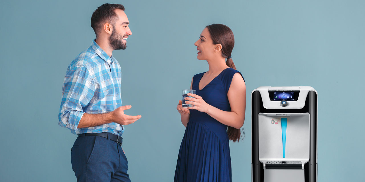 Un homme et une femme se tiennent à côté d'une fontaine à eau et discutent.