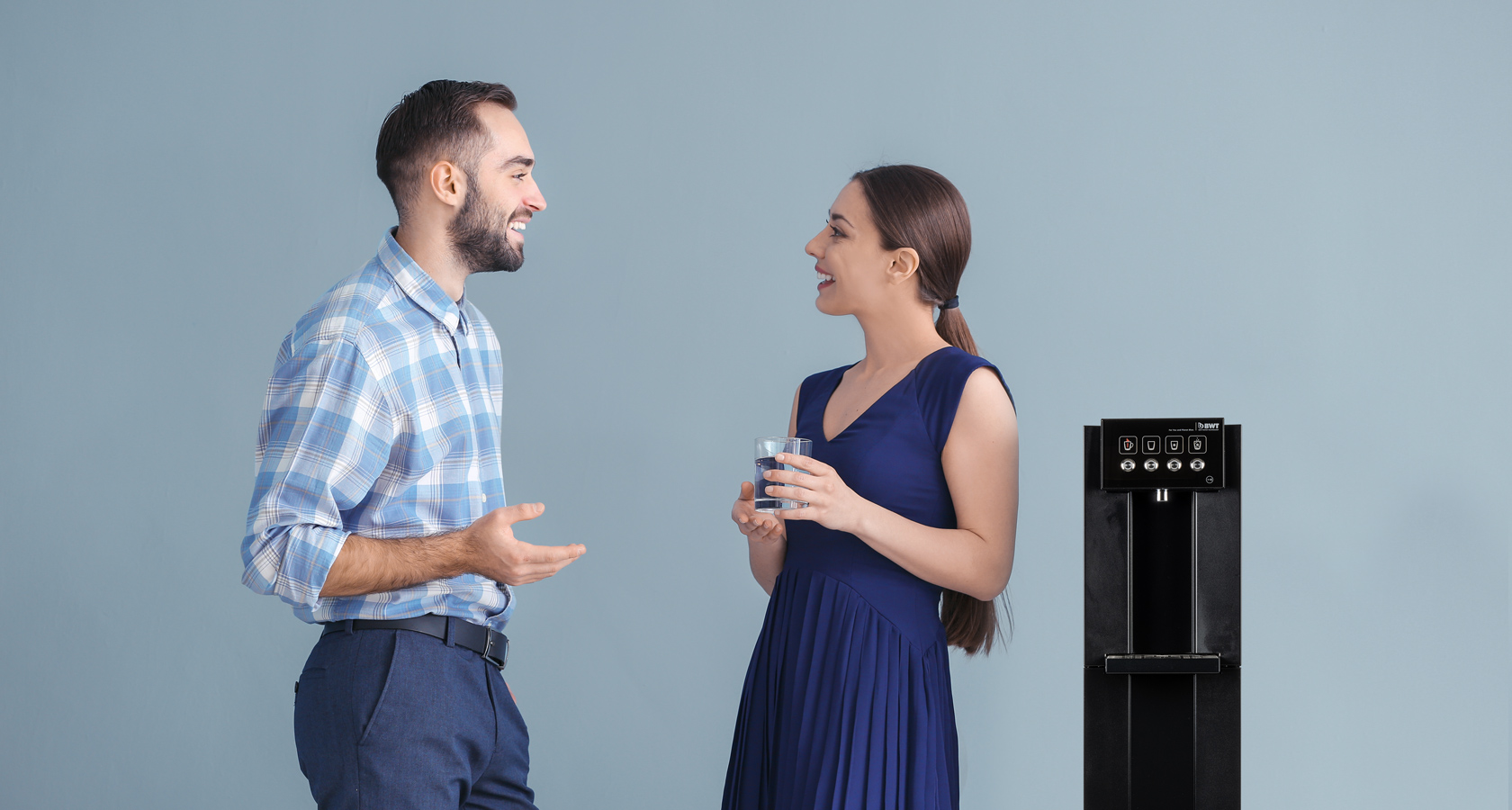Un homme et une femme se tiennent à côté d'une fontaine à eau de BWT.
