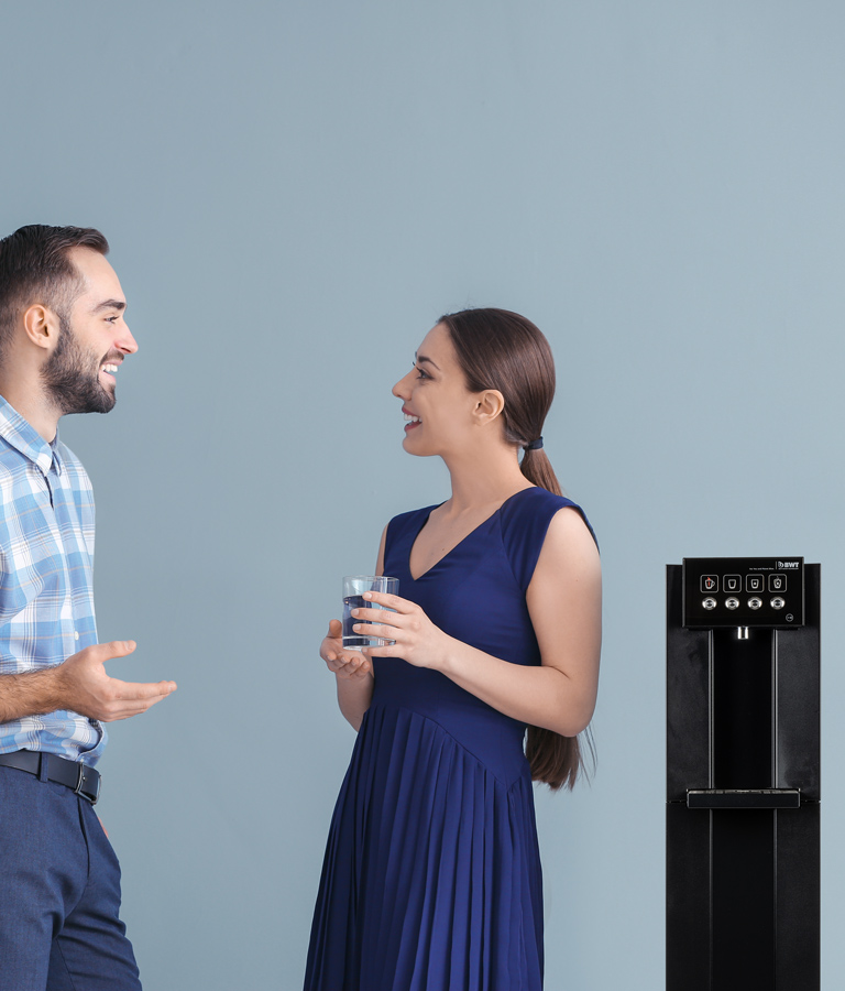 Un homme et une femme se tiennent à côté d'une fontaine à eau de BWT.