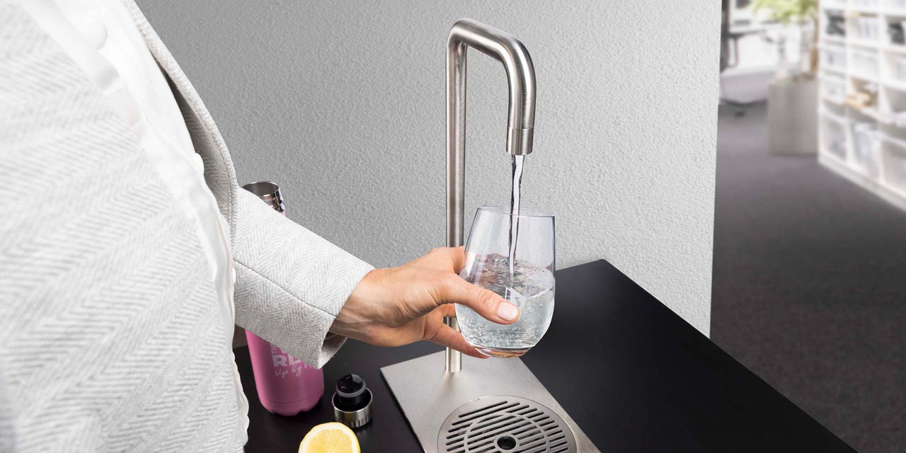 Une femme tient un verre sous un robinet.