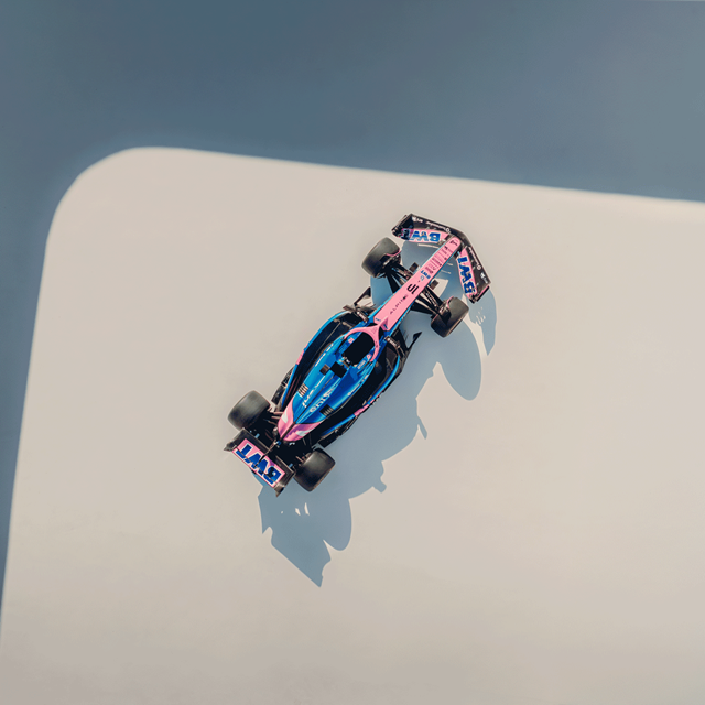 Une voiture de Formule 1 aux couleurs bleu et rose, photographiée d'en haut.