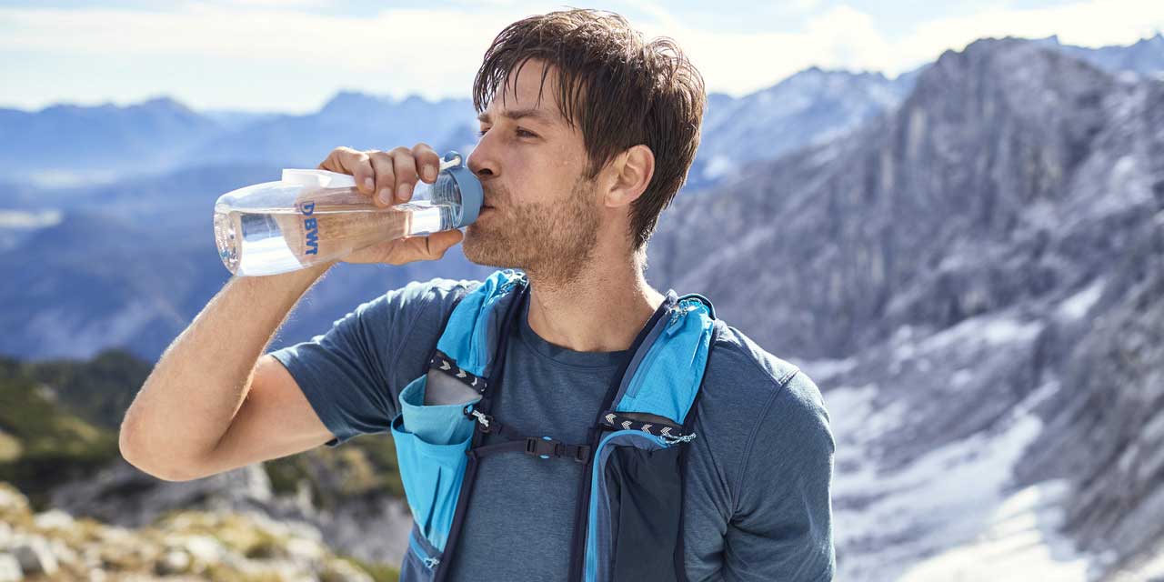 Un homme en randonnée boit de l'eau BWT