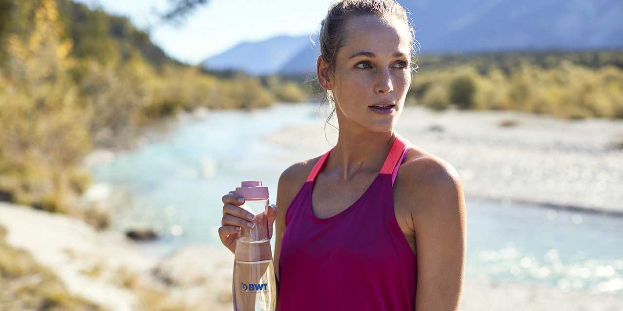 Une femme sportive boit de l'eau BWT