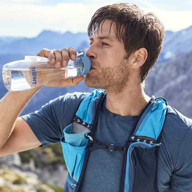 Un homme en randonnée boit de l'eau BWT