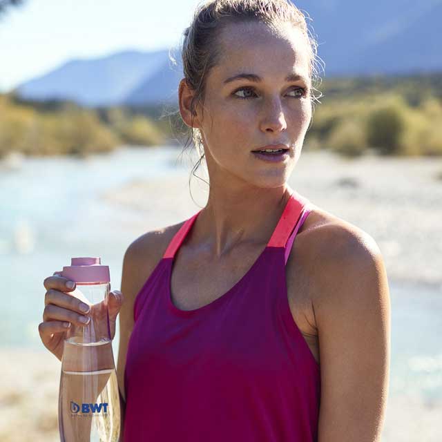 Une femme sportive boit de l'eau BWT