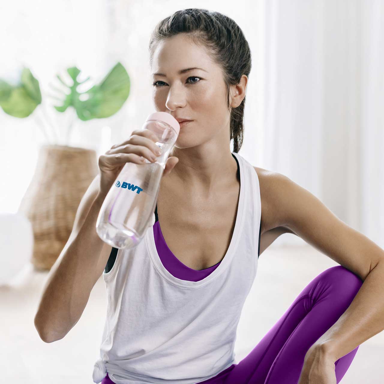 Une femme boit dans une gourde après le yoga