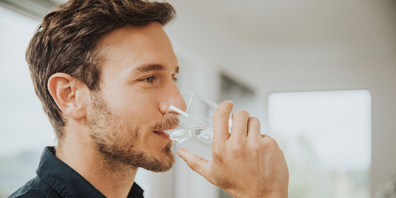 Homme boit un verre d'eau