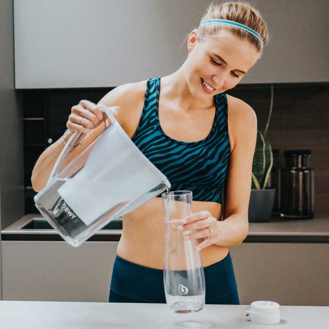 une femme se sert de l'eau d'une carafe filtrante