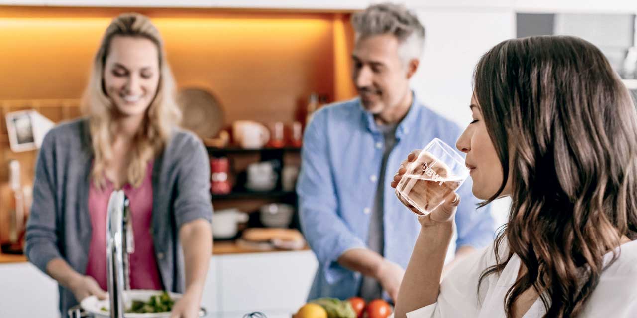 une femme boit de l'eau à la maison