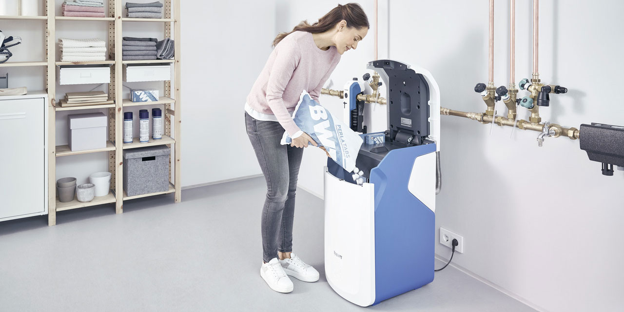 Une femme recharge le sel de son adoucisseur d'eau