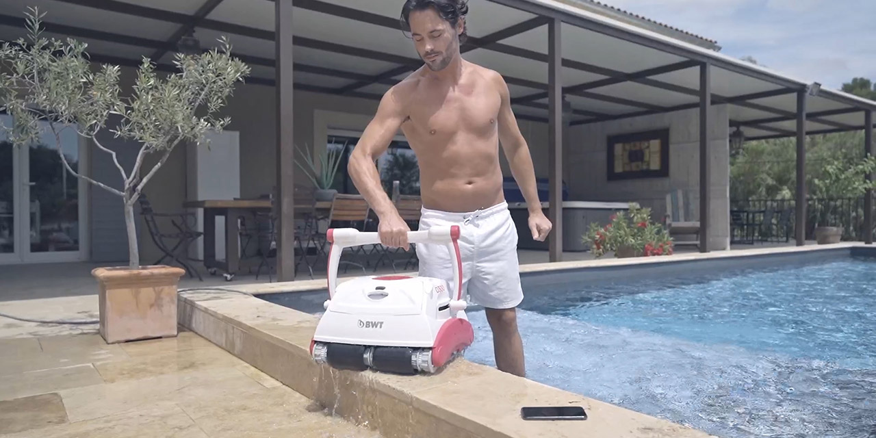 Un homme porte un robot de piscine