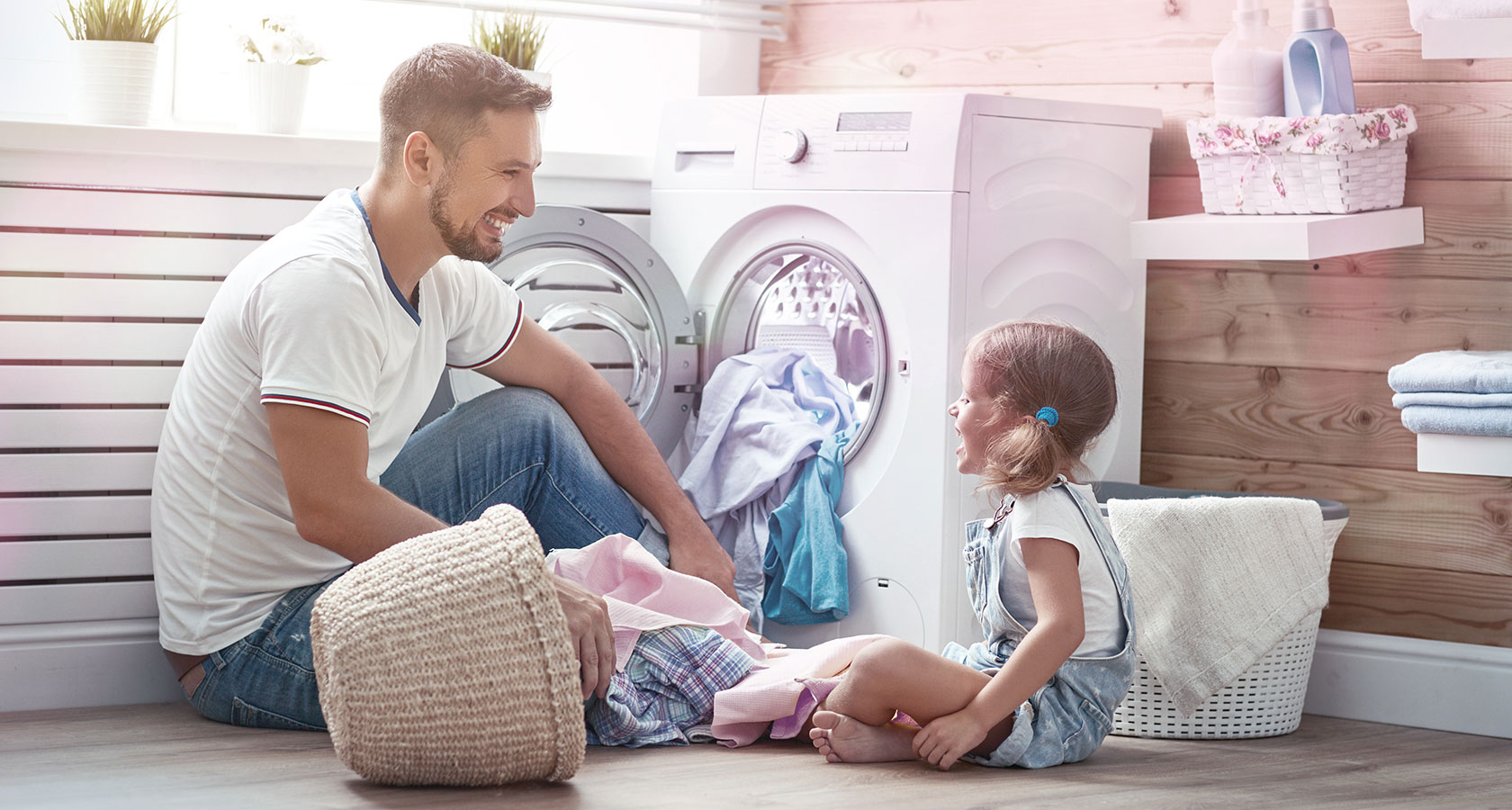 Un père et sa fille devant une machine à laver