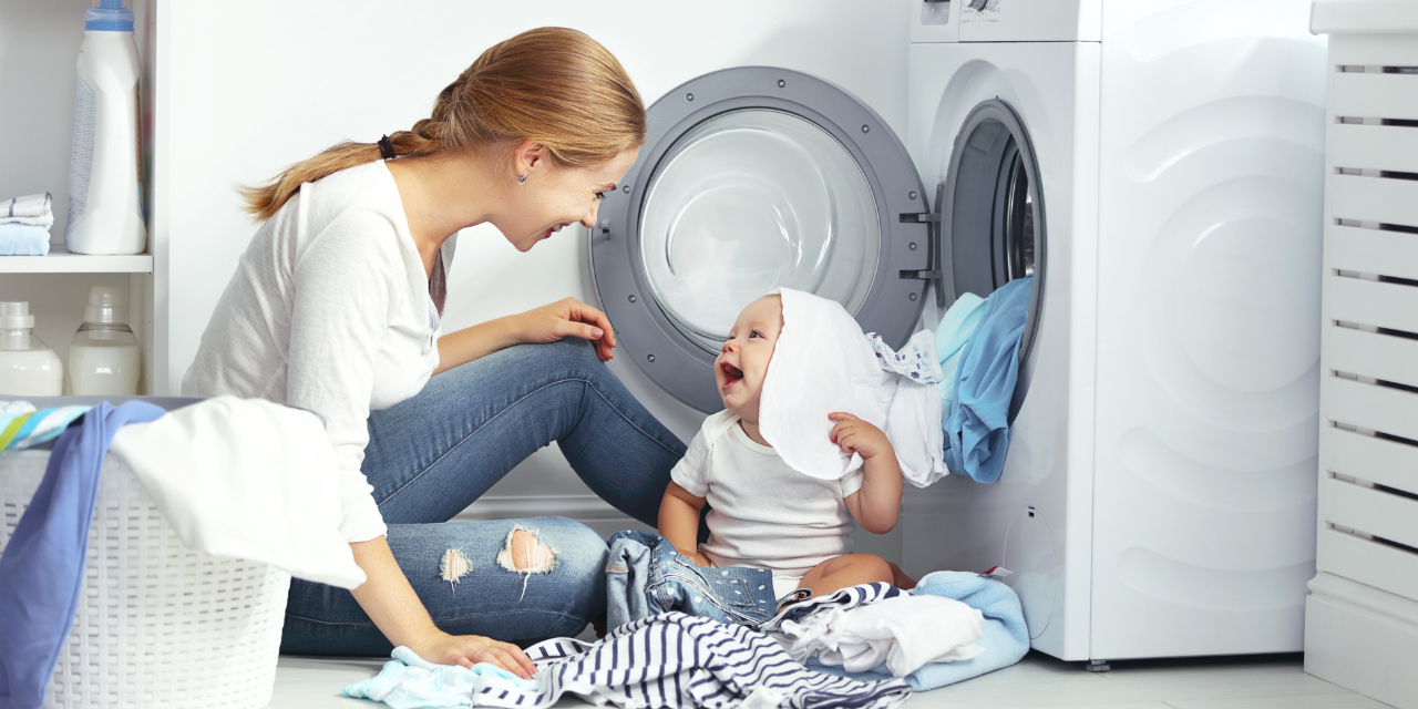 Lágy víz előnyei otthona mosógépénél hölgy kisgyerekkel mos